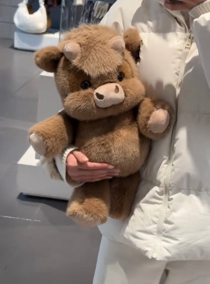 Person holding a brown cow plushie in an indoor setting