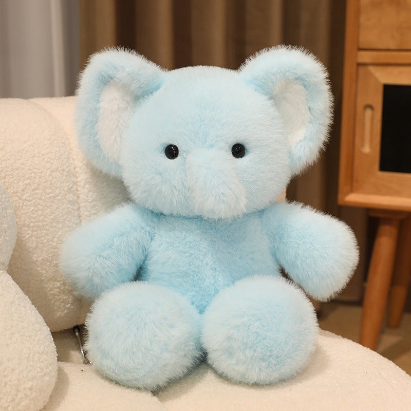 Light blue teddy bear sitting on a white surface with a neutral background