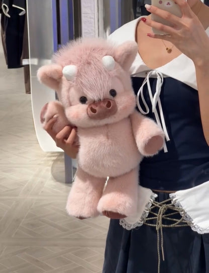 Person holding a pink cow plush  toy in front of a mirror.