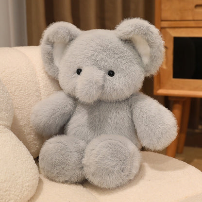 Gray teddy bear sitting on a beige surface with a wooden cabinet in the background